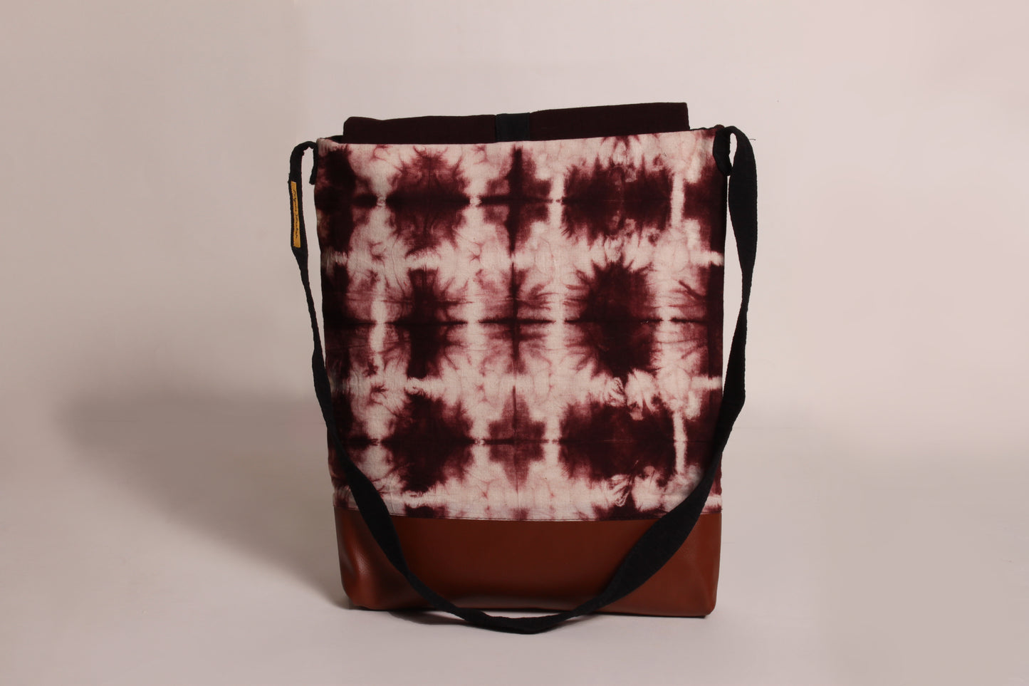 Back view of Brown Tile Artist Bag made from cotton fabric with faux leather, a magnetic snap closure, and a pocket 