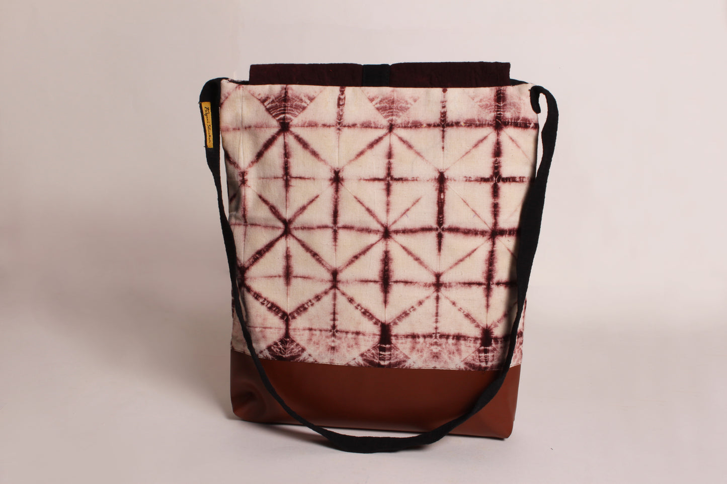 Back view of Brown  Tessellation Artist Bag made from cotton fabric with faux leather, a magnetic snap closure, and a pocket 