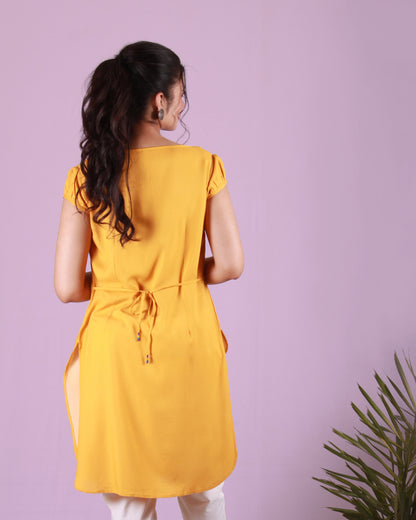 Back view of yellow Calla Lily Tunic in cotton blend with slight puff cap sleeves and drawstring detail