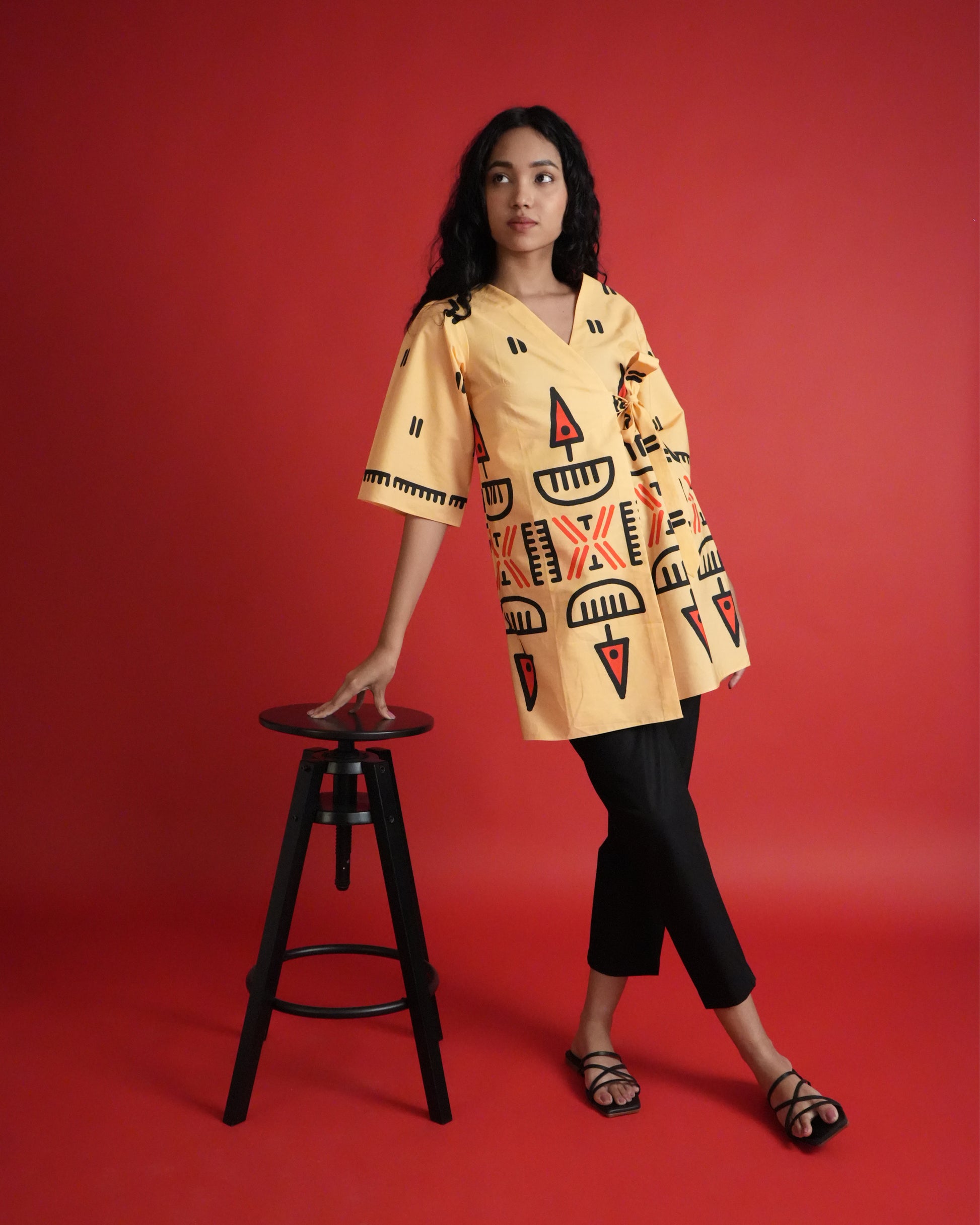 Front view of Owu Cotton Co-ord Set in pastel orange with tribal prints, tie detail, flared sleeves, and black pants