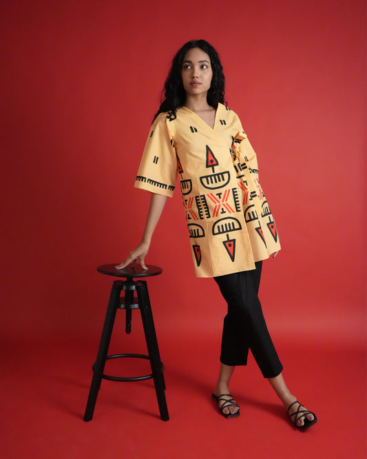 Front view of Owu Cotton Co-ord Set in pastel orange with tribal prints, tie detail, flared sleeves, and black pants